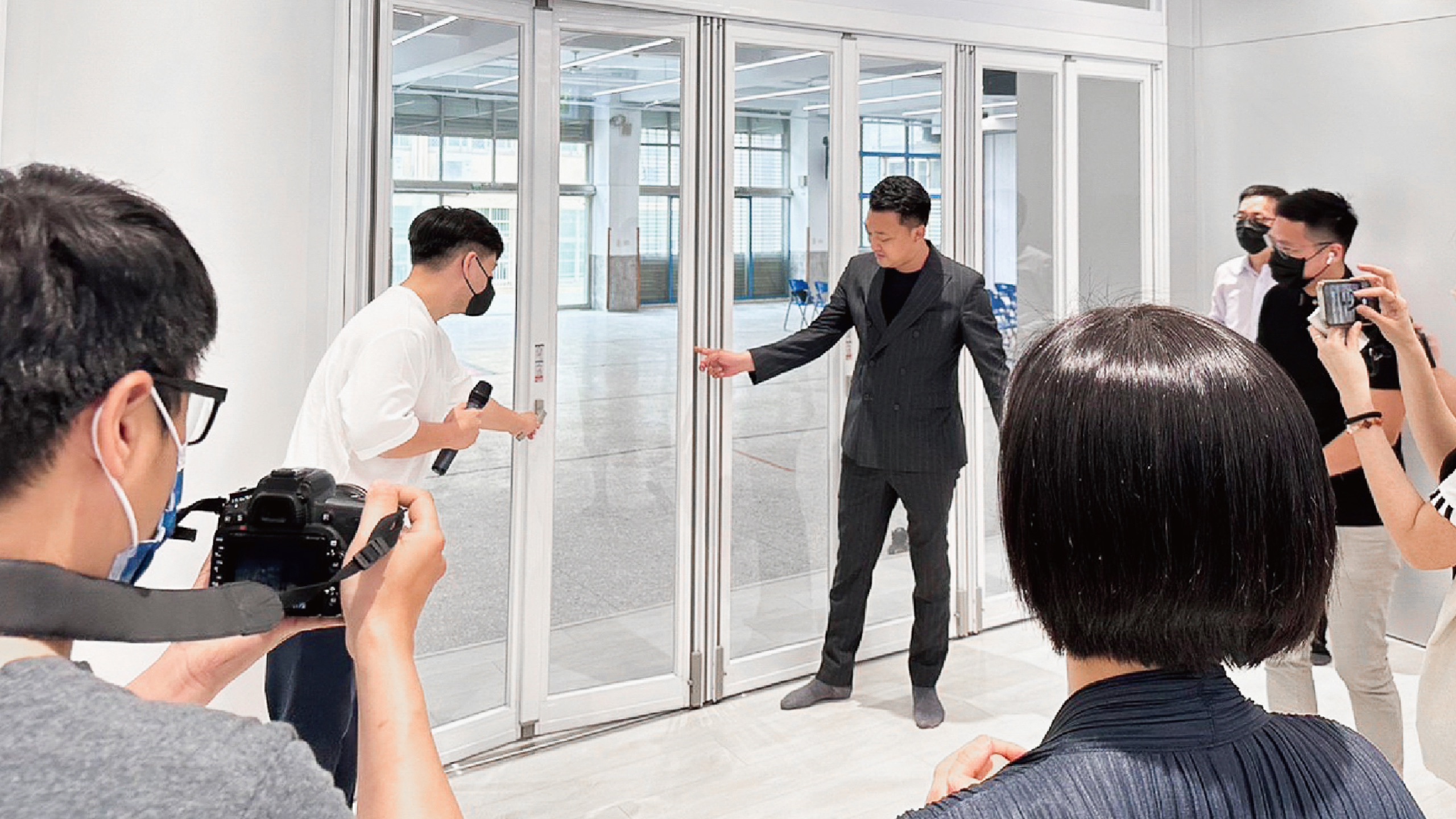 校園美感改造成果發表：現場示範白色鋁框摺疊門的開啟操作，媒體於旁攝影記錄